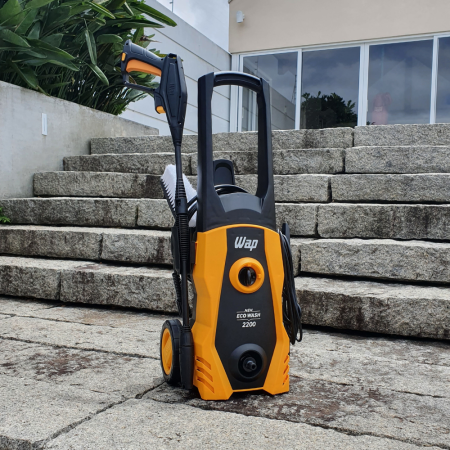 Lavadora de alta pressão WAP Eco Wash 2200 amarela sobre degraus de pedra, com folhagens ao fundo.